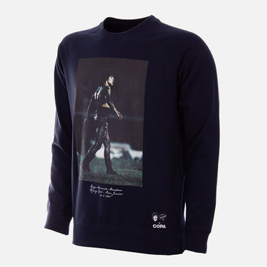 Flat-lay of the black sweater featuring Maradona on a muddy pitch with white print