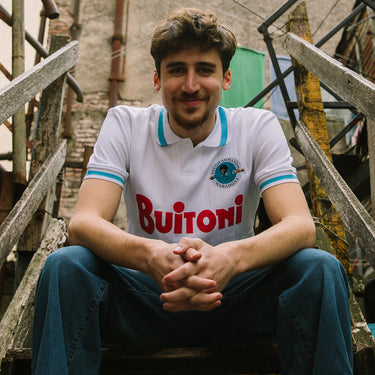 Lifestyle shot of a model sitting on stairs wearing the Maradona X COPA Napoli 1986 - 87 Away Retro Football Shirt.