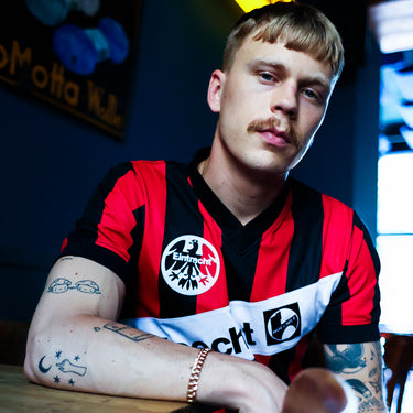Eintracht Frankfurt 1990 - 91 Retro Football Shirt Red & Black Lifestyle worn by a model in a dimly lit indoor setting.