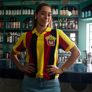 Leones Negros udeG 1974 Retro Football Shirt Yellow, Red & Black Lifestyle worn by a model in a casual bar setting.