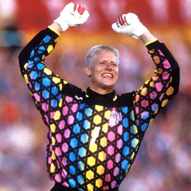 Vintage goalkeeper wearing a multicolored geometric-patterned jersey, raising arms in celebration