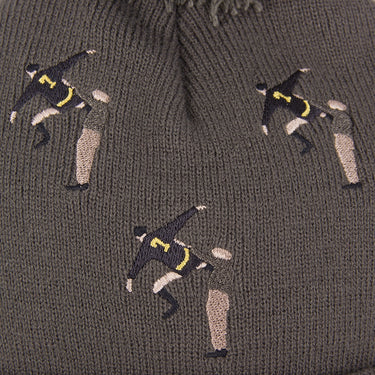 Close-up of the embroidered bicycle kick footballers pattern on the brown fabric of the beanie