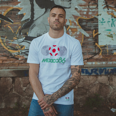 Model wearing the Mexico 1986 World Cup T-shirt, standing against a graffiti wall, showcasing the retro football design.