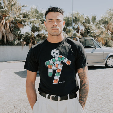 Model wearing the Italy 1990 Ciao Mascot T-Shirt, standing outdoors, showcasing the retro football-inspired design.