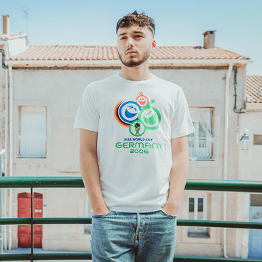 Model Wearing Germany 2006 World Cup T-Shirt standing outdoors, showcasing the tournament emblem on the white tee.