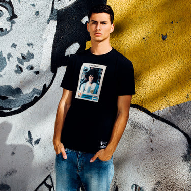 Model wearing the Maradona x COPA Argentina Football Sticker T-Shirt, standing against a graffiti wall.