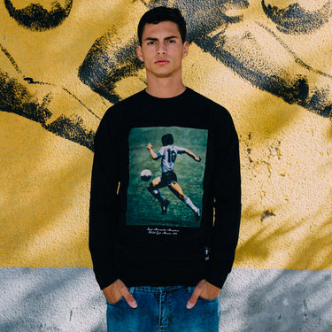 Model wearing the Maradona x COPA World Cup 1986 Sweater in front of a mural of Maradona
