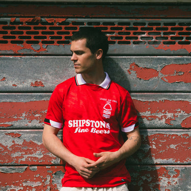 Lifestyle shot of a model wearing the Nottingham Forest 1988 - 89 Retro Football Shirt, standing against a brick wall.