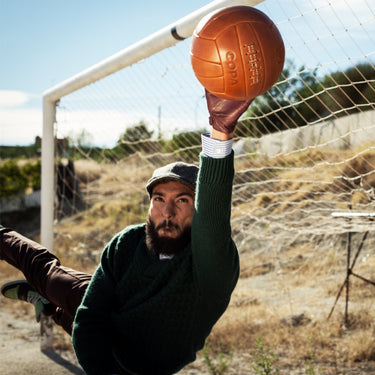 Person holding COPA Retro Football 1950's with the ball above their head in an outdoor setting